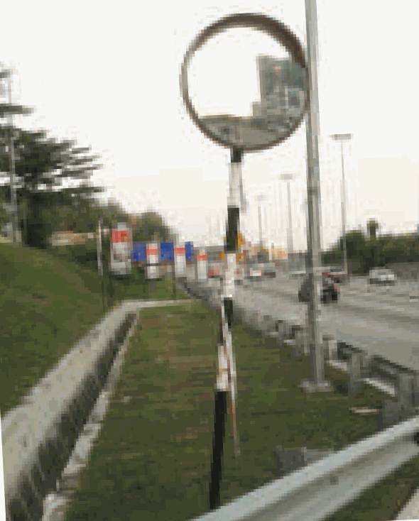 A round mirror on a pole at a road bend